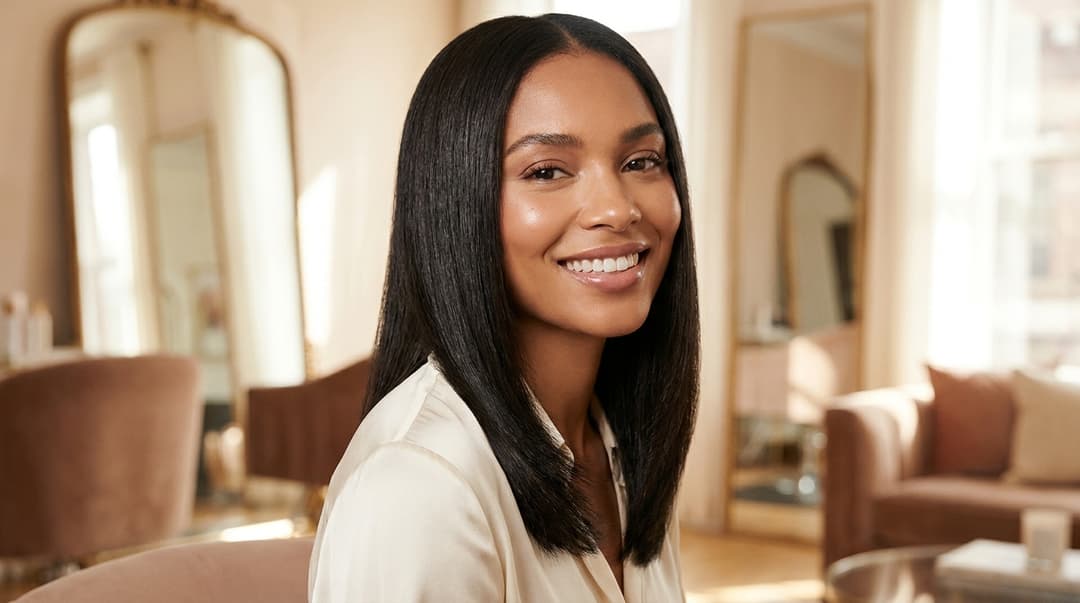 Beautiful woman with glowing skin and a glossy silk press hairstyle in soft light