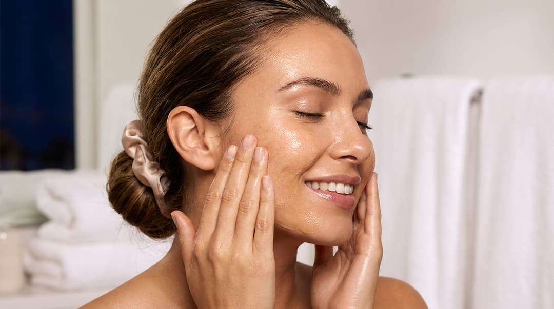 Beautiful woman using an oil cleanser to remove makeup and sunscreen