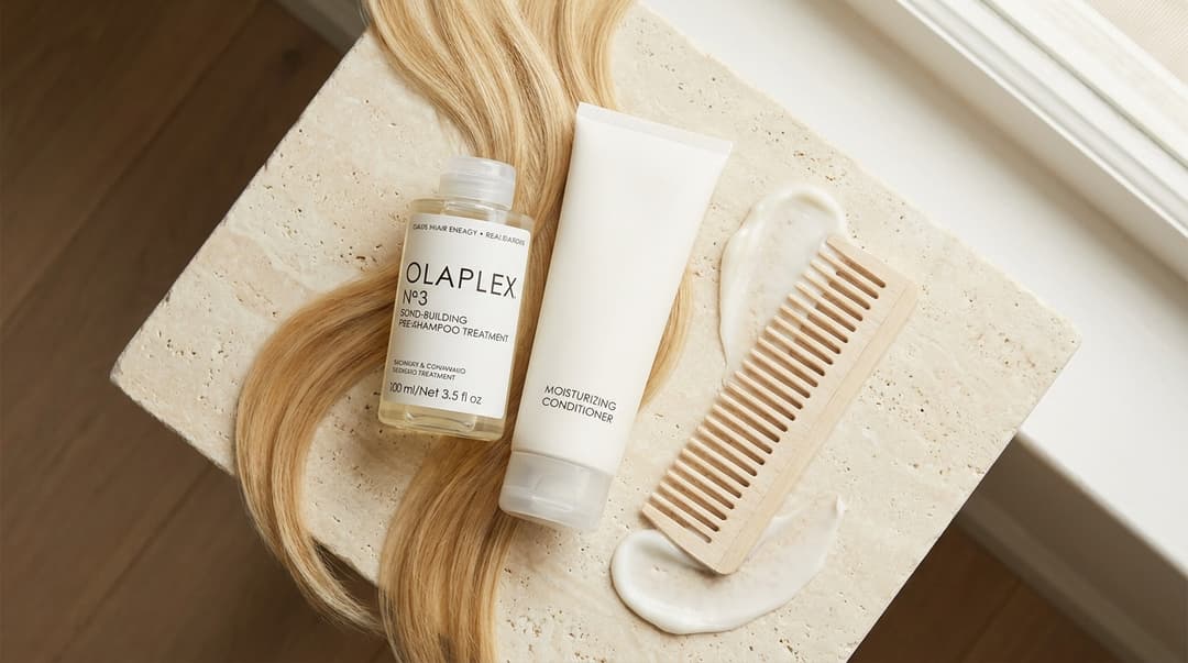 Olaplex bond treatment, conditioner, and wide-tooth comb arranged on an ivory surface.