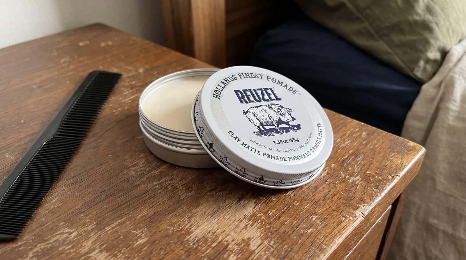 Reuzel Clay Matte Pomade 95g tin on a walnut dresser