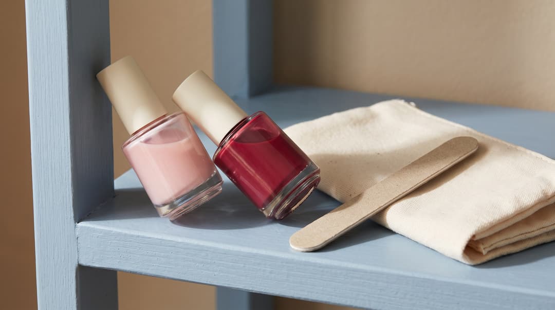 Two nail-polish bottles beside a file and a folded cloth.