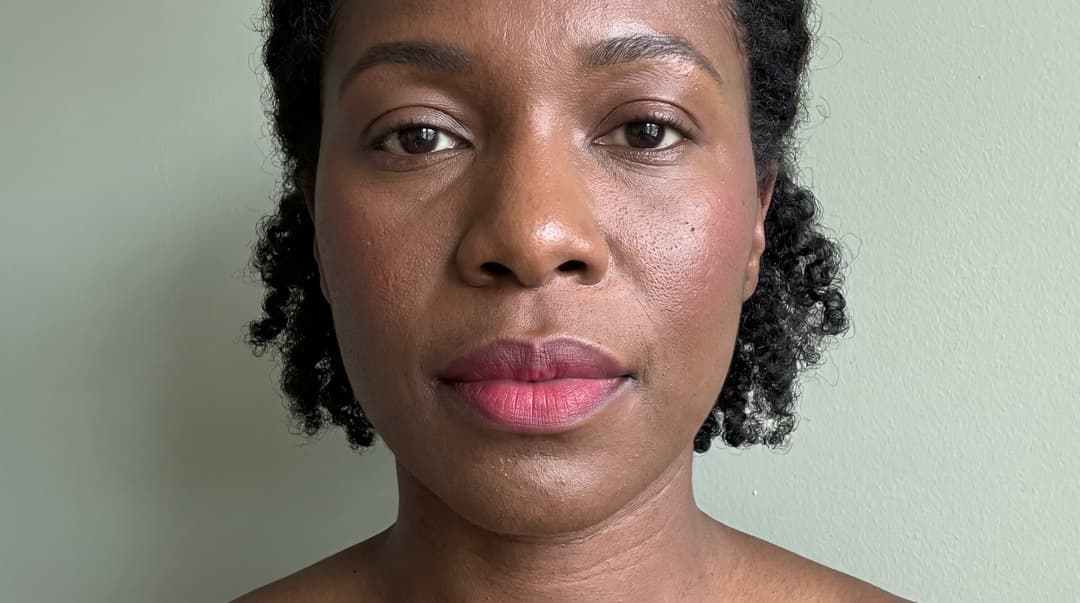 Close-up of diffused raspberry lip color and a softly powdered complexion on deep skin. AI-generated editorial illustration showing placement and finish ideas; no specific product performance is depicted.