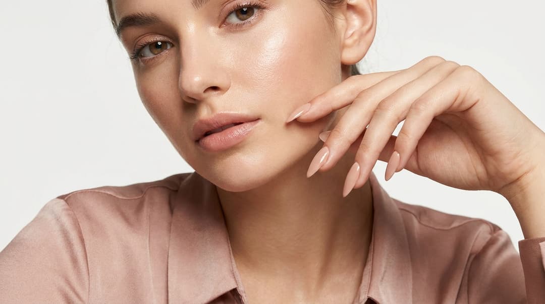 Close-up of a woman with glowing skin showing almond and oval nails