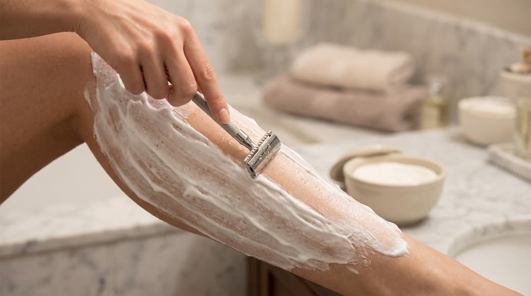 Woman shaving her leg with the grain using shaving cream