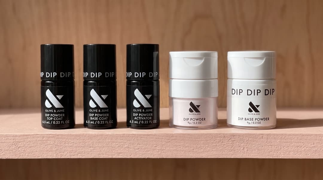 Olive & June dip liquids and powder jars; selected kit components shown. AI editorial illustration.